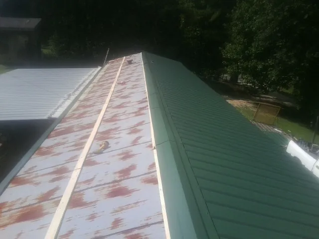 Old rusted panels beside newly installed green metal roofing — Wind Damage Roof Repair by Roofing Brothers in South Rockwood