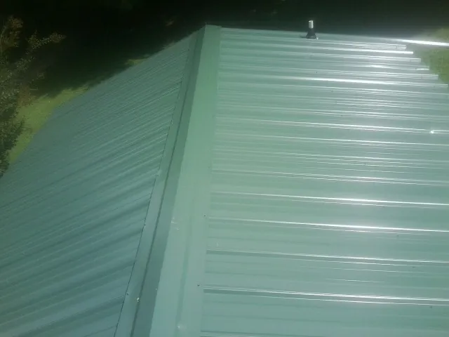 New green metal panels meeting at the ridge of a roof — Flat Roof Repair work by our crew in South Rockwood