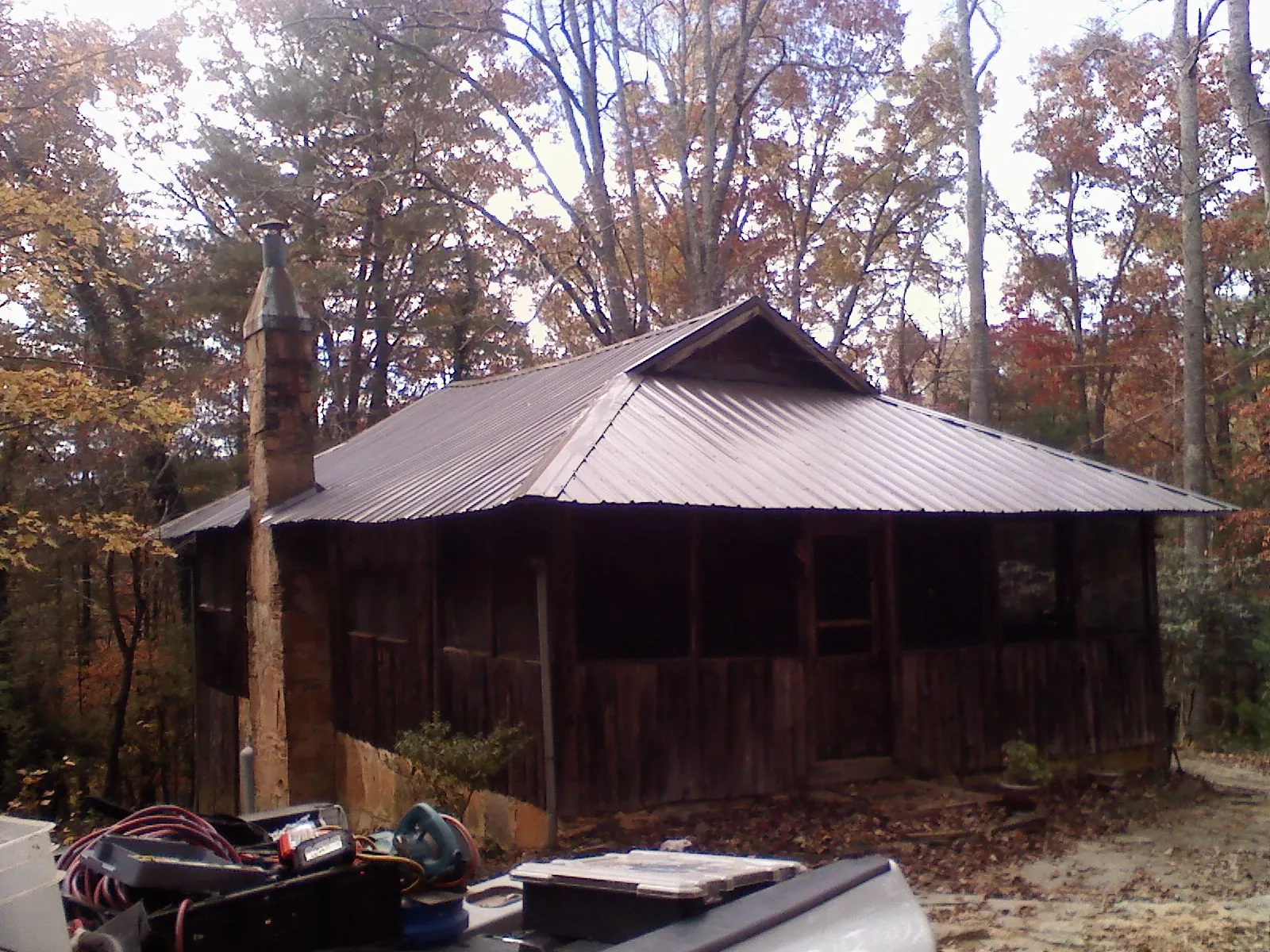 Brown metal hip roof on an old cabin with a stone chimney in South Rockwood