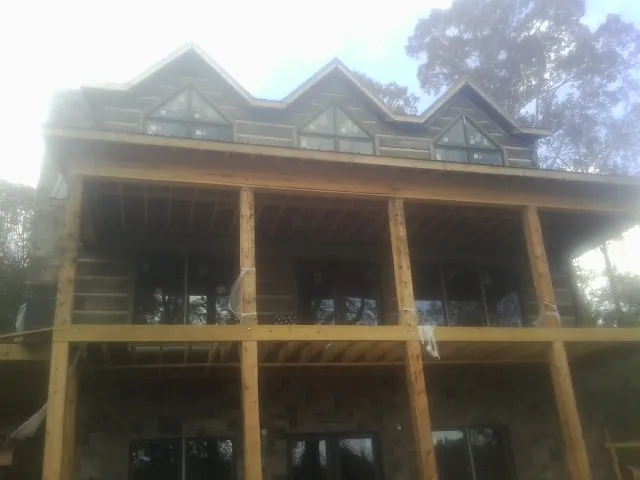 Dormers and porch framing on a large log home under construction — Roof Coating work by our crew in South Rockwood