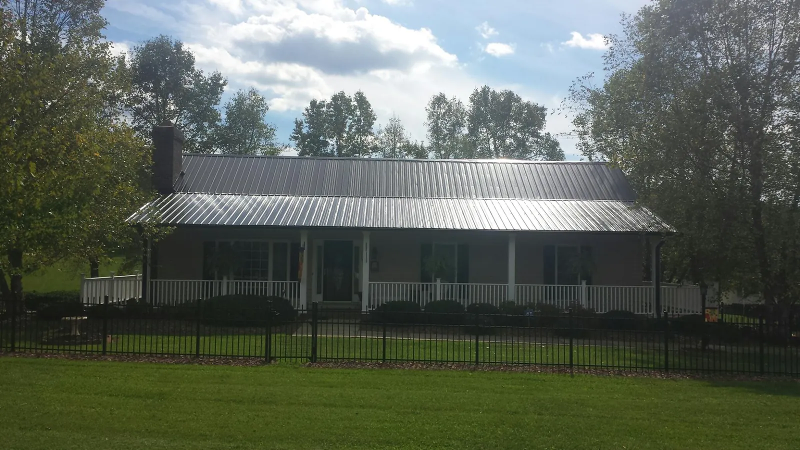 Gray metal roof on a brick ranch with a full width front porch — Gutter Guard Installation work by our crew in South Rockwood