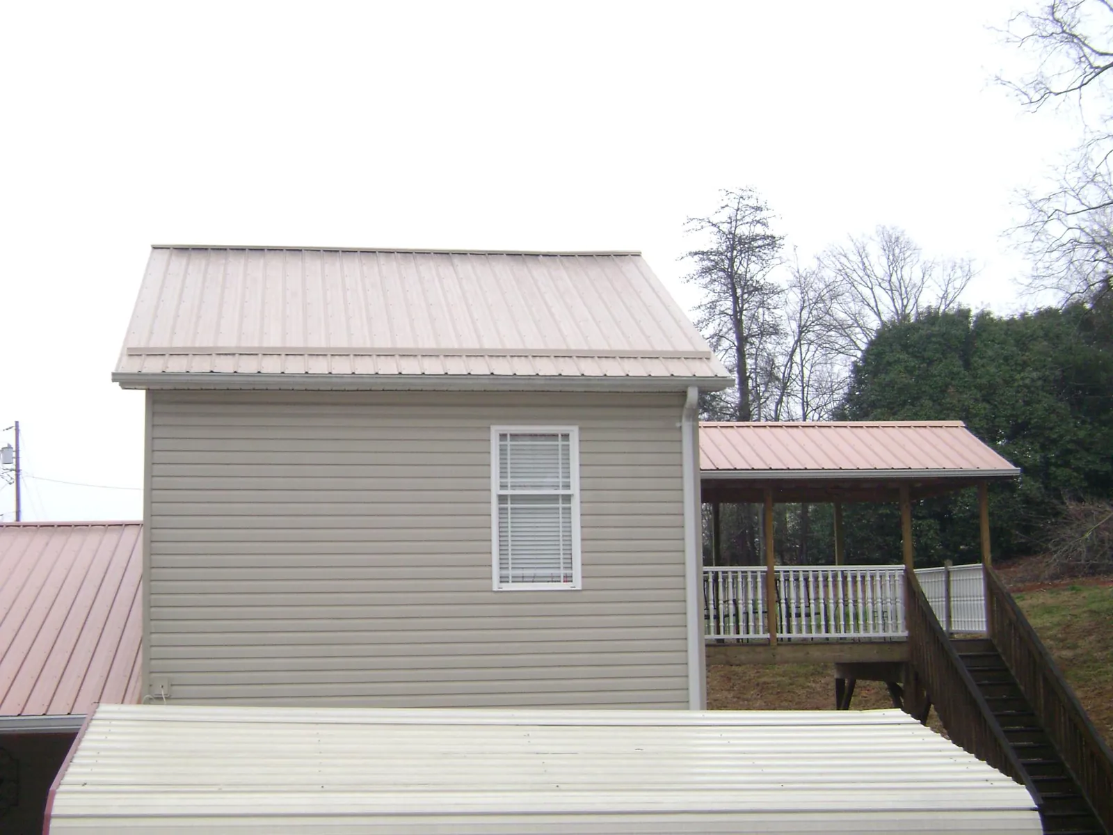 Tan metal roofs on a two story addition and attached porch, from a Roof Replacement job in South Rockwood